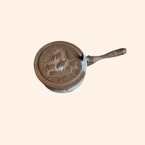 Bronze pan with a ship design on its surface.