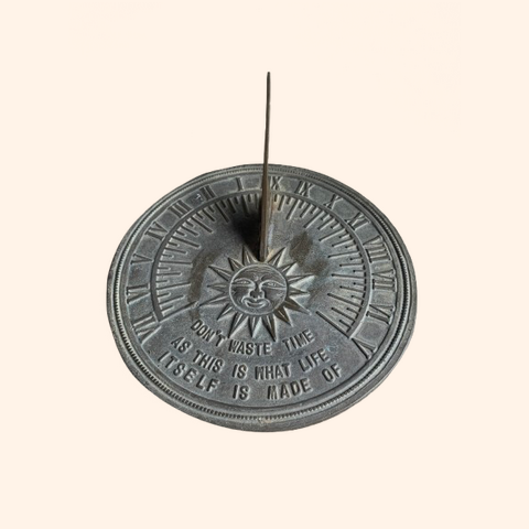 Metal sundial with a central gnomon and decorative design.