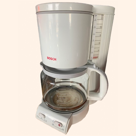 White coffee maker with a glass carafe and water gauge.