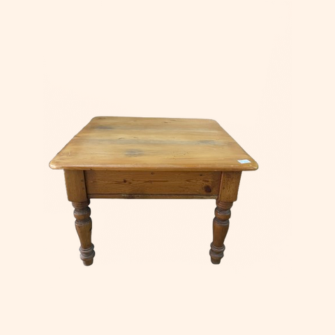 Wooden table with four turned legs and a square top.