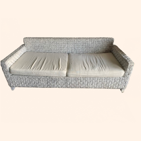 Woven two-seater sofa with cream cushions.