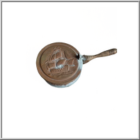 Bronze pan with a ship design on its surface.